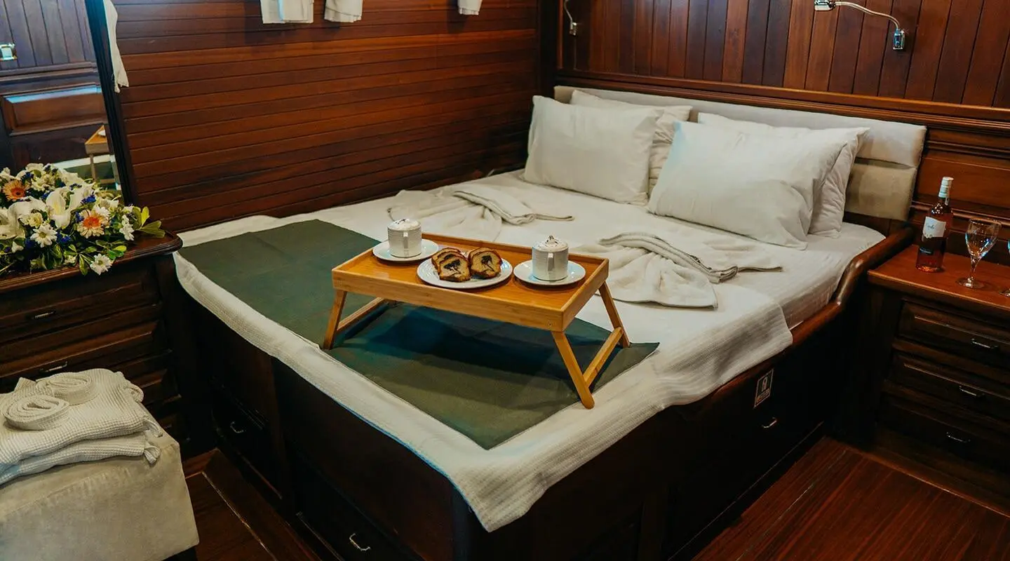 Luxurious indoor yacht cabin with double bed and side table at sunset