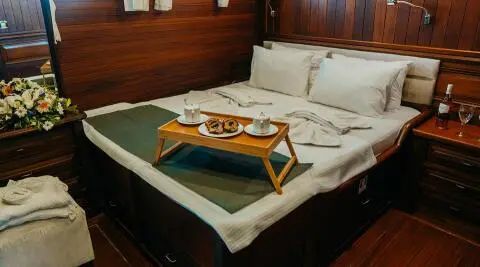 Luxurious indoor yacht cabin with double bed and side table at sunset