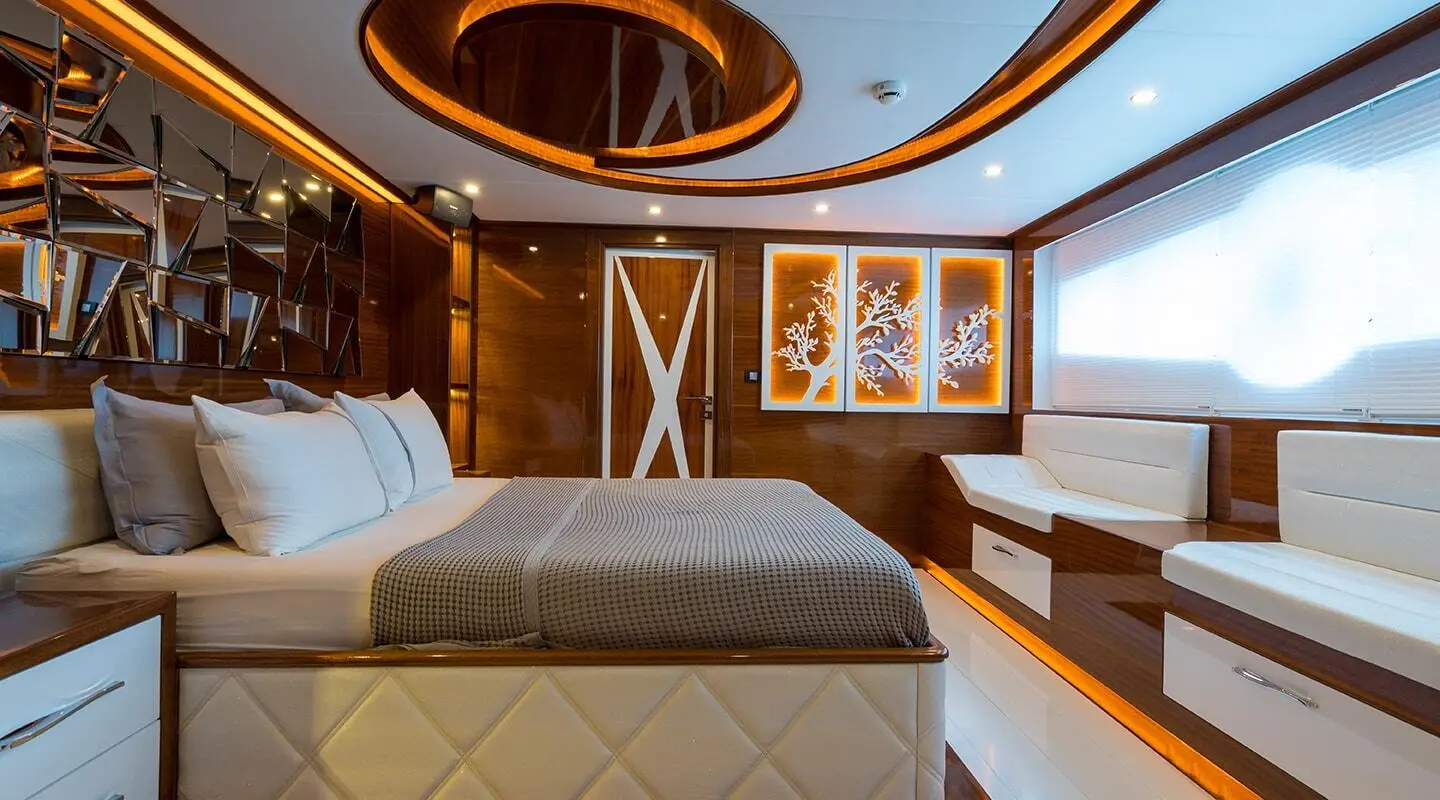 Interior view of a yacht cabin with a large bed, wooden accents, and ceiling skylight