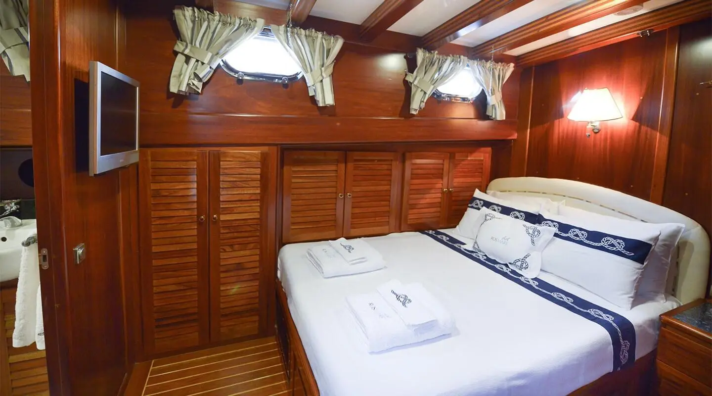 Interior cabin aboard Ros Mare yacht with two single beds and wooden panels