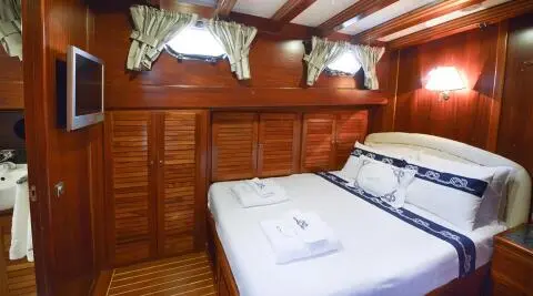 Interior cabin aboard Ros Mare yacht with two single beds and wooden panels