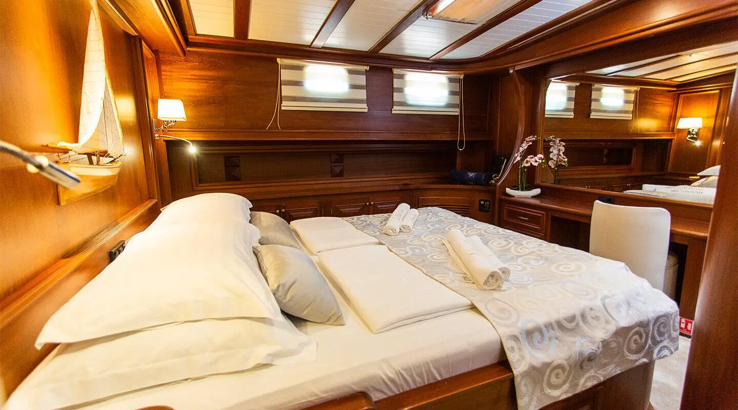Dolce Vita yacht interior: cozy bed with white pillows and wooden panels