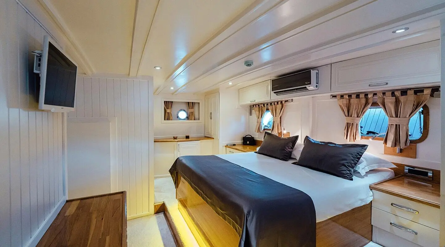Interior of Maske yacht cabin with bed, blue throw, warm lighting