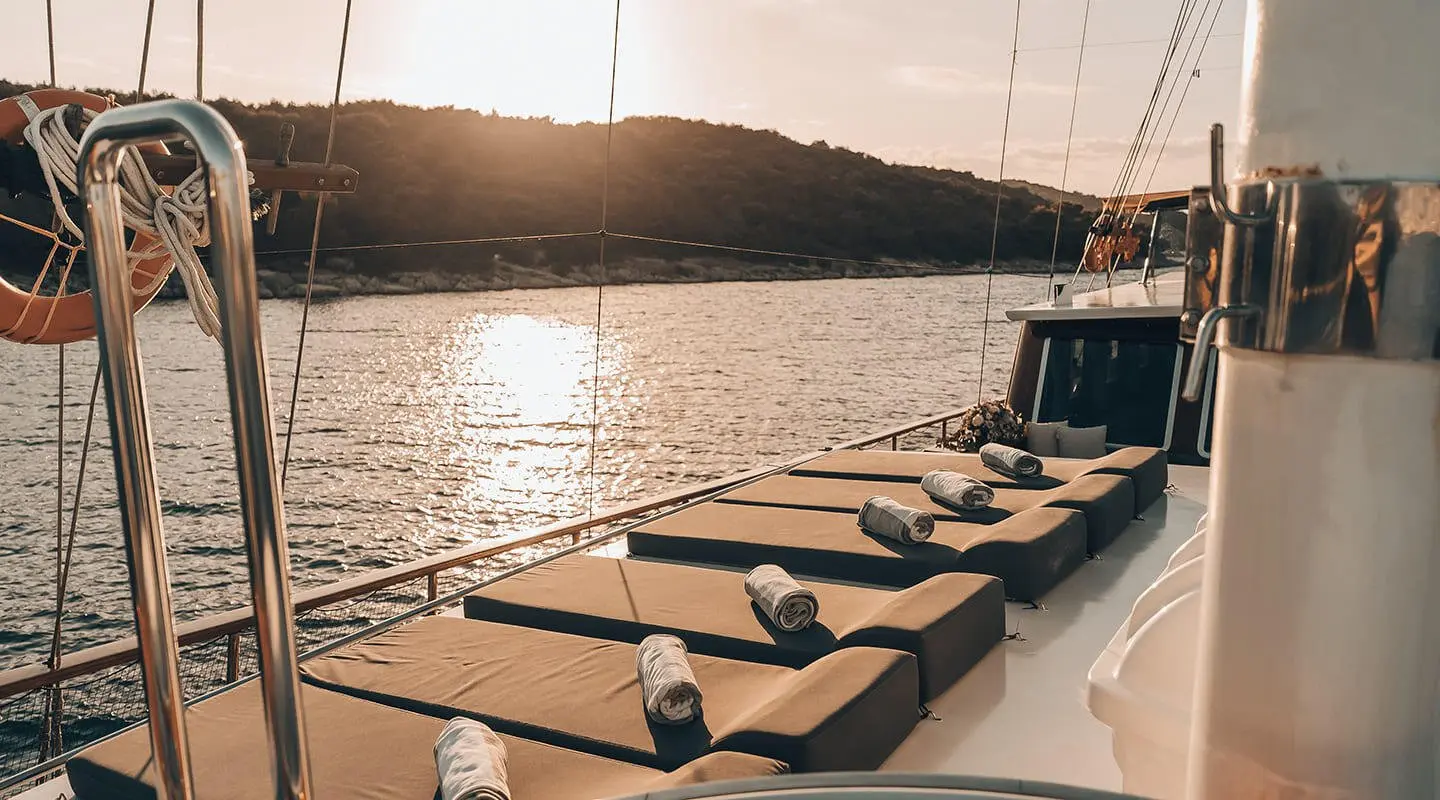 Luxurious sailing yacht deck at sunset with moored stern and calm water