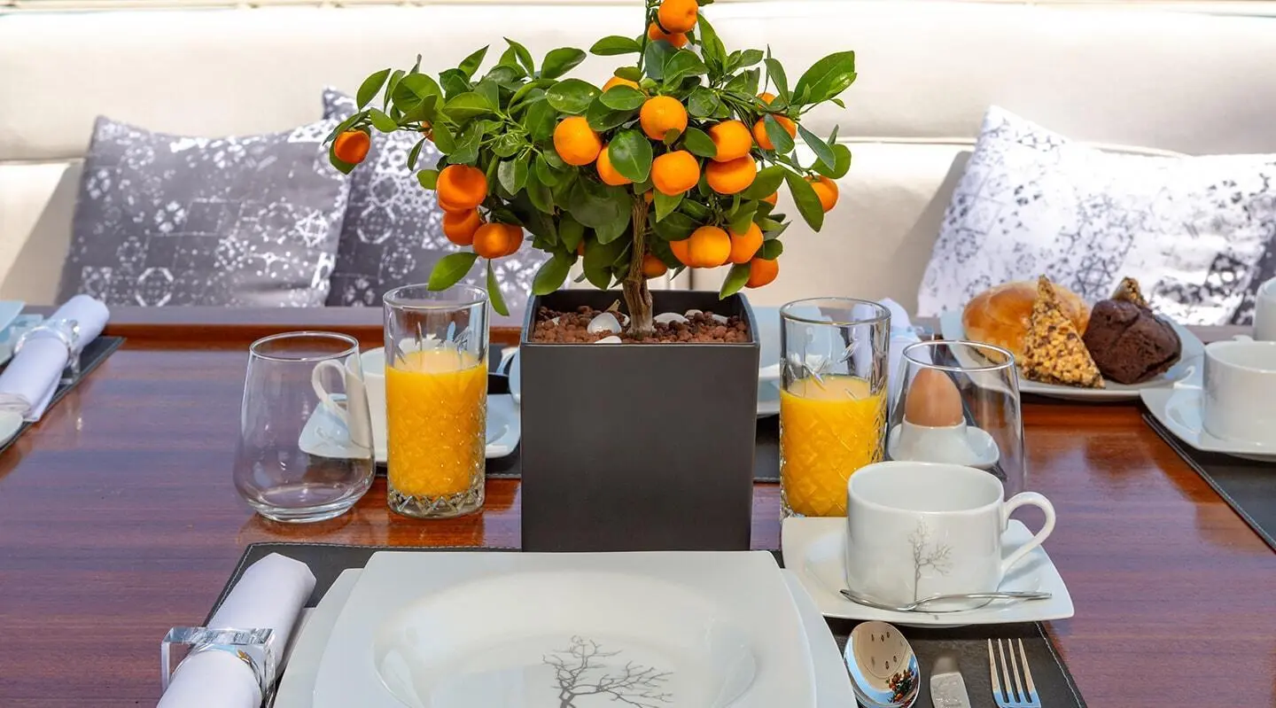 Divine yacht dining setup with orange centerpiece, white plates, and orange drinks