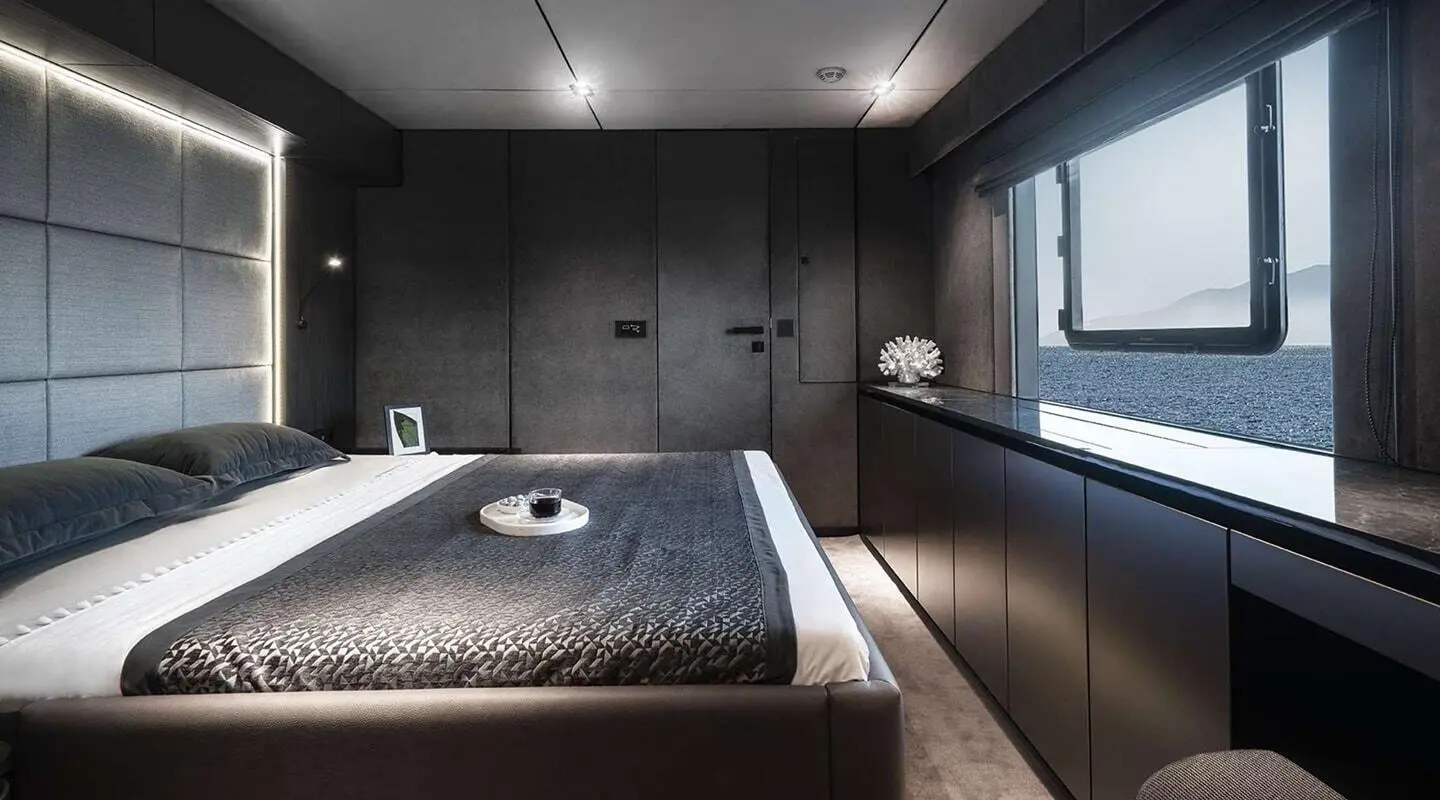 Alteya yacht interior with dark wood cabinets, bed, and bedside lights at dusk