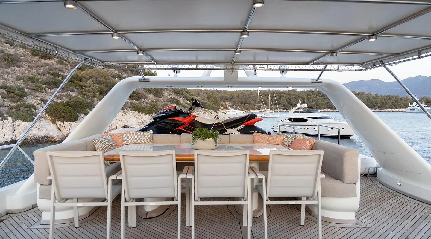 Aquila yacht dining area under a covered deck with sea view and chairs