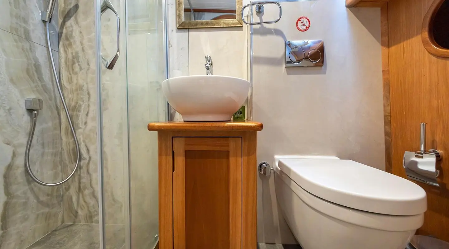 Small wooden stand with sink in a bathroom aboard Bodrum Queen yacht