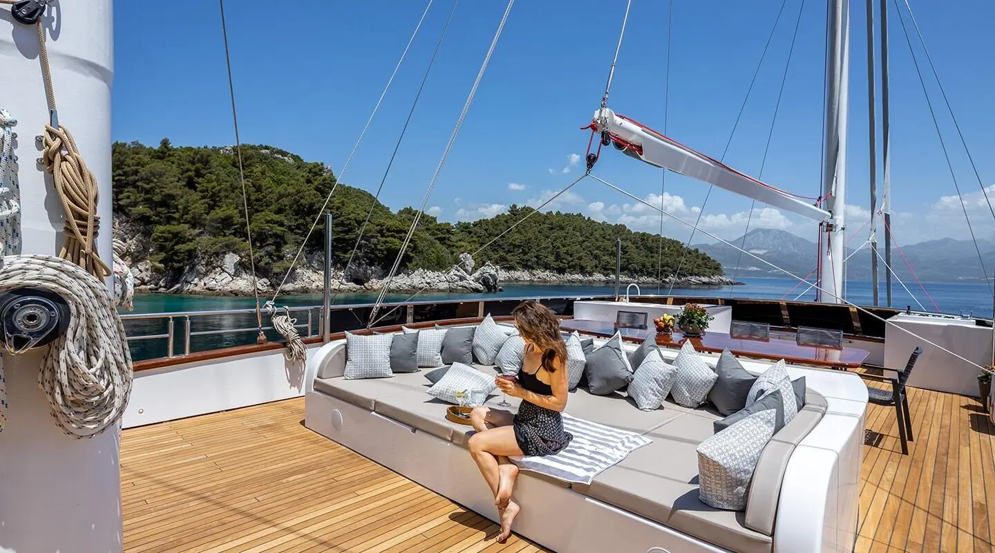 Yacht Love Story docked at sunset with guests relaxing on deck and sailboat masts