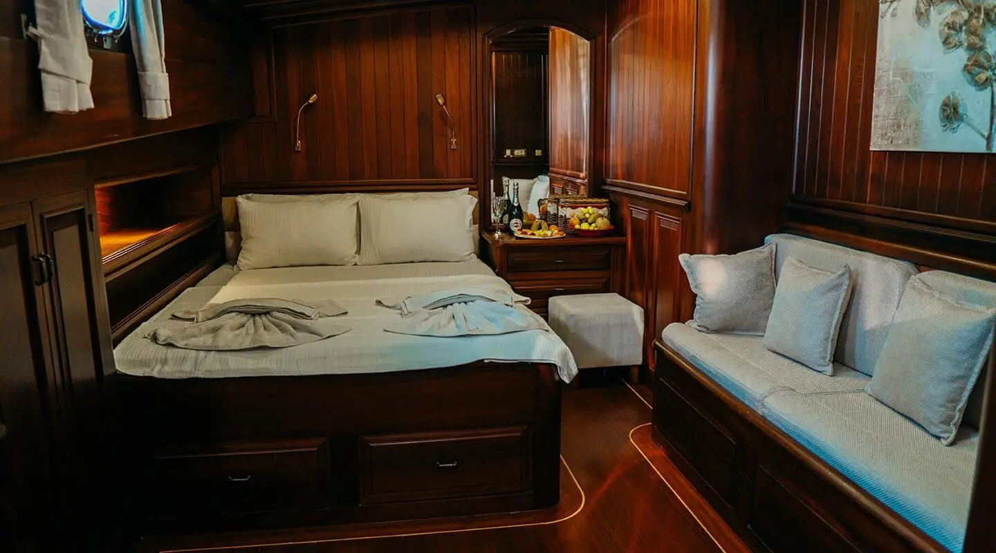 Interior of Wicked Felina yacht: two white beds, dark wood panels, warm lighting