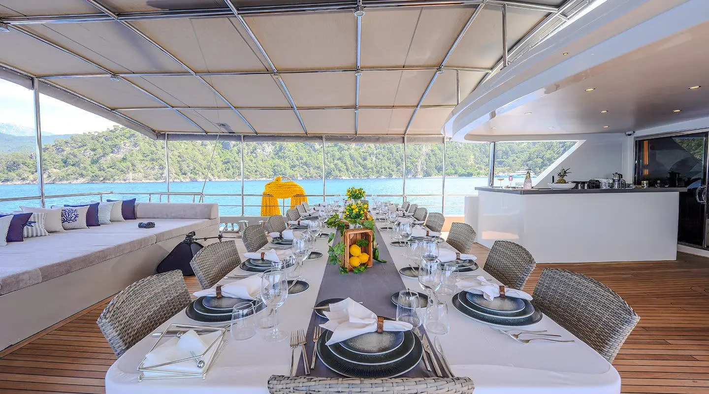 King Of The Sea on a sunlit yacht deck with a long dining table set for guests