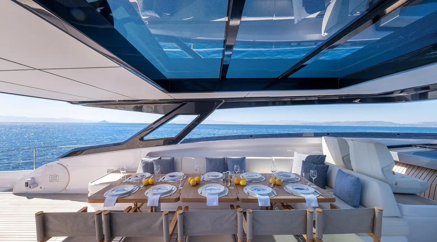 Spica yacht dining area with seated guests on deck at sunset