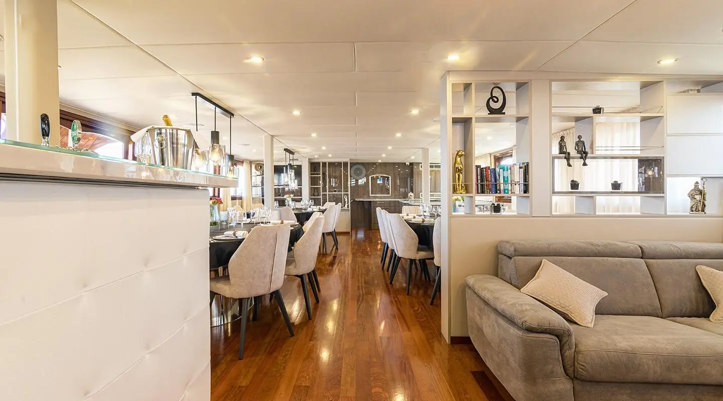 Interior of Melody luxury yacht: polished wooden floor, seating, dining area, and kitchen visible