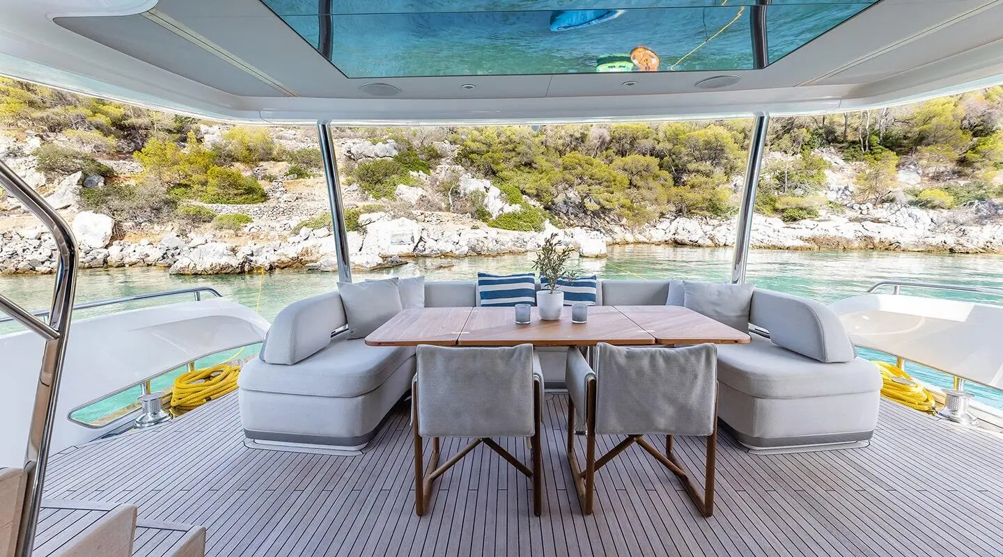 Vista yacht dining area on deck with table and chairs at sunset