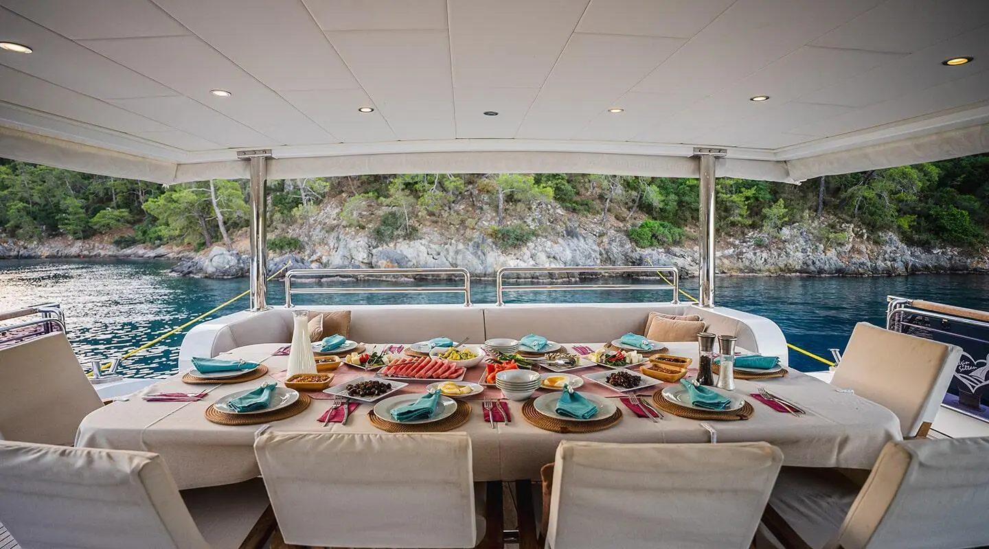 Belgin Sultan yacht deck with sun loungers and tableware on a shaded seating area