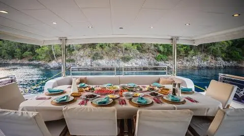 Belgin Sultan yacht deck with sun loungers and tableware on a shaded seating area