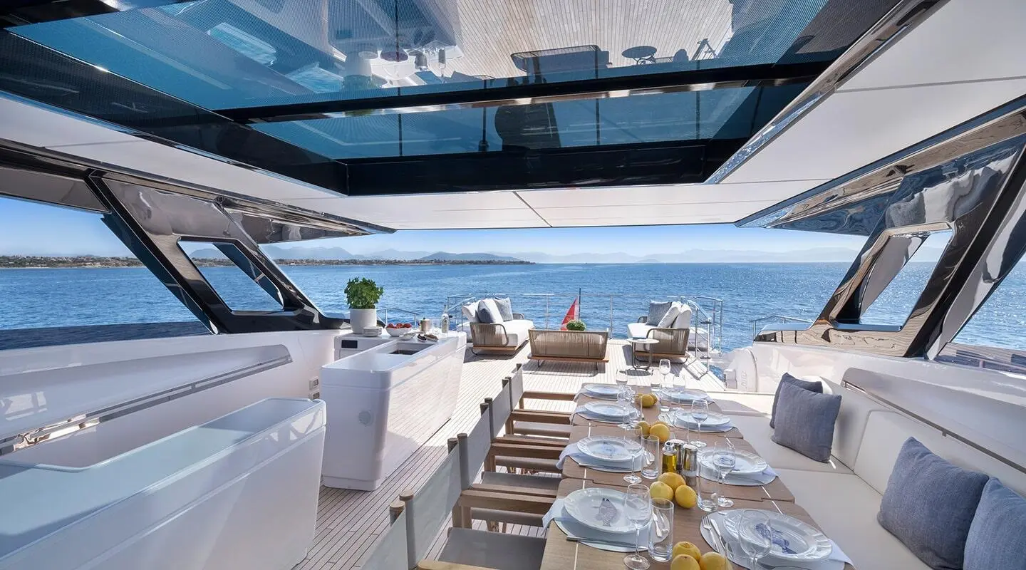 Spica yacht dining area on deck with cushioned seating and glass railings