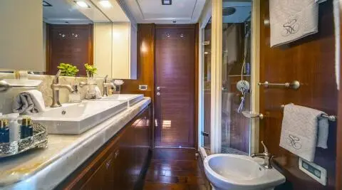 Interior view of a luxury motor yacht Seventh Sense with polished wood, bar seating, and doorway to deck