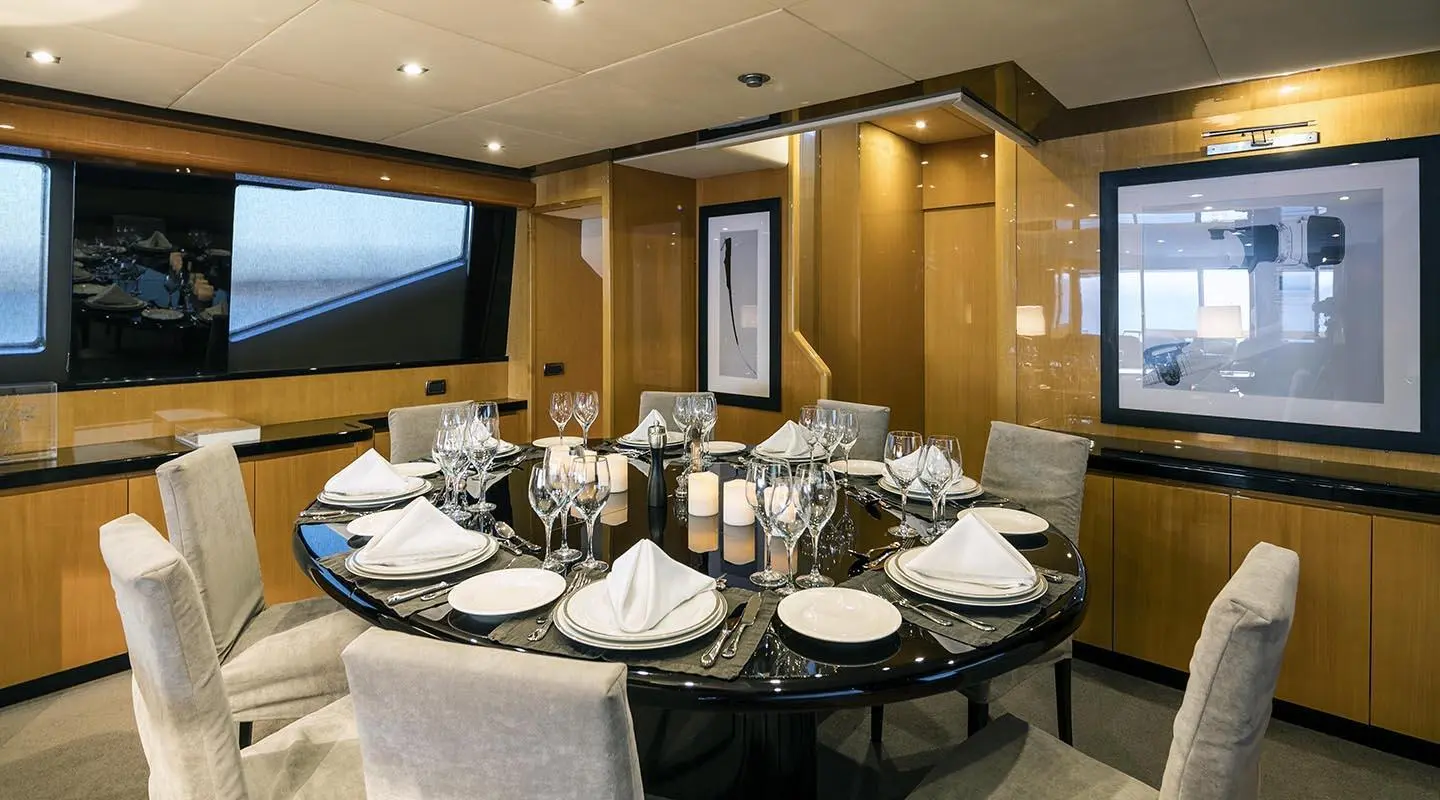 Interior dining area on a luxury yacht with round table set for dinner at dusk