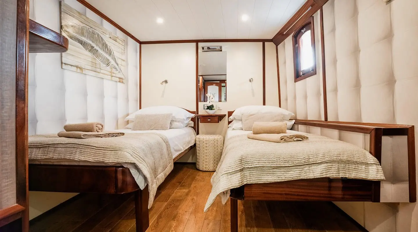 Luxurious yacht Mendula cabin interior with two beds, wood floor, and large window views