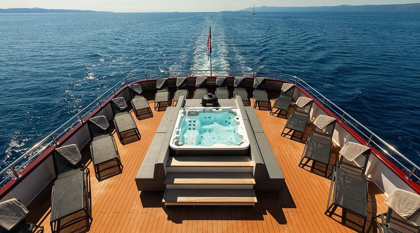 Aft deck of the yacht with a hot tub and seating along the sides overlooking the sea