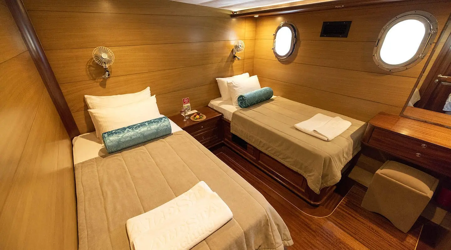 Kayhan 4 yacht charter scene with two cushioned beds in warm wood cabin