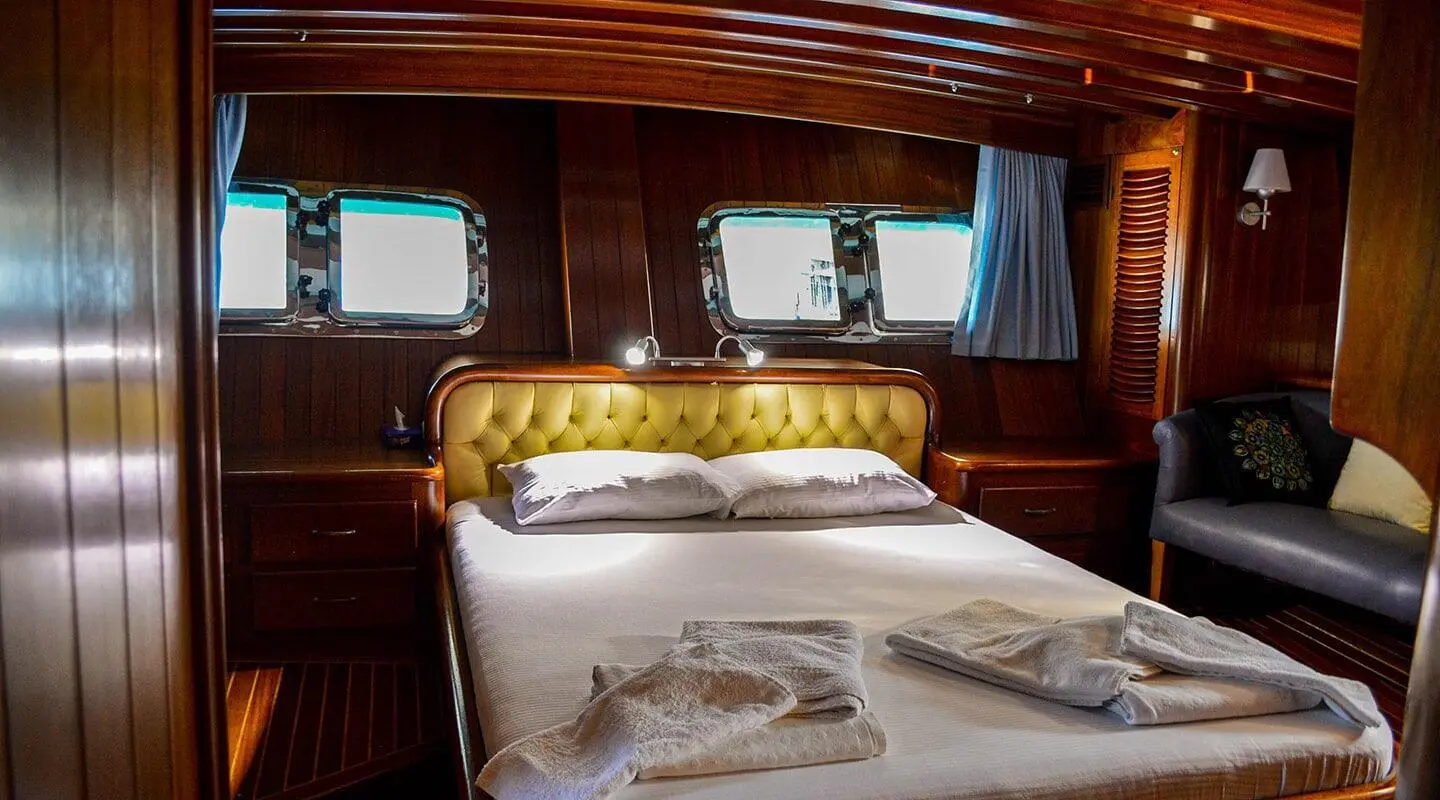 Enderim A yacht bedroom with tufted leather headboard and wood-panelled walls