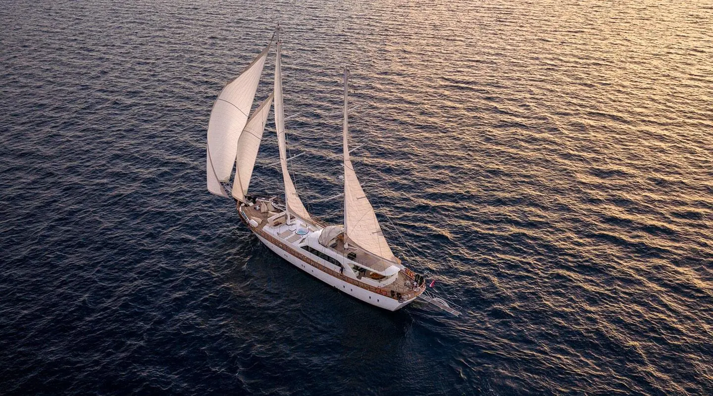 Sailing yacht with sails up on open sea, viewed from above
