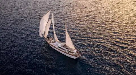 Sailing yacht with sails up on open sea, viewed from above