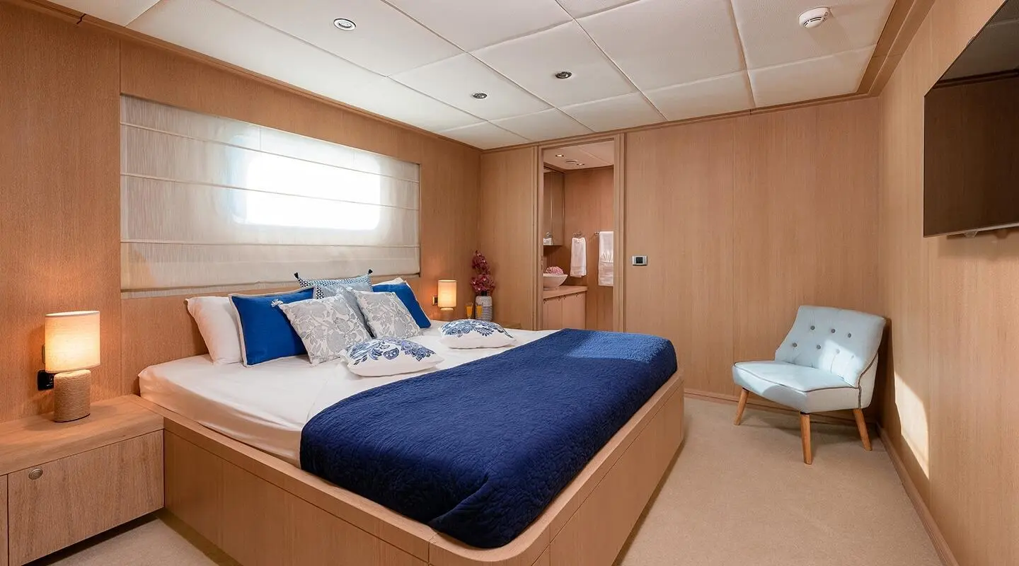Grace yacht bedroom with blue bedspread, wooden walls, window, and built-in furniture