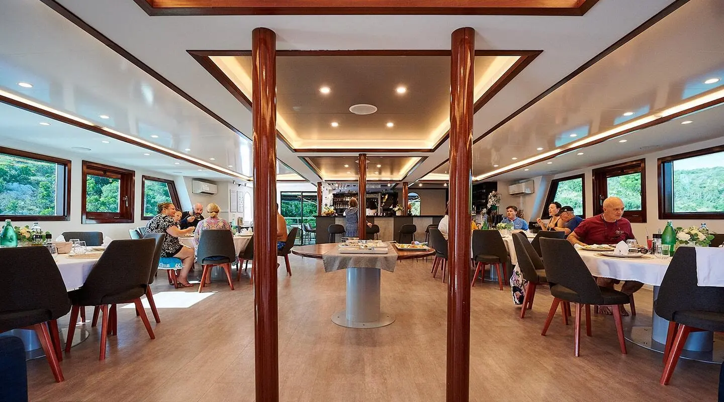Lupus Mare yacht interior with dining area and guests at sunset