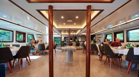 Lupus Mare yacht interior with dining area and guests at sunset