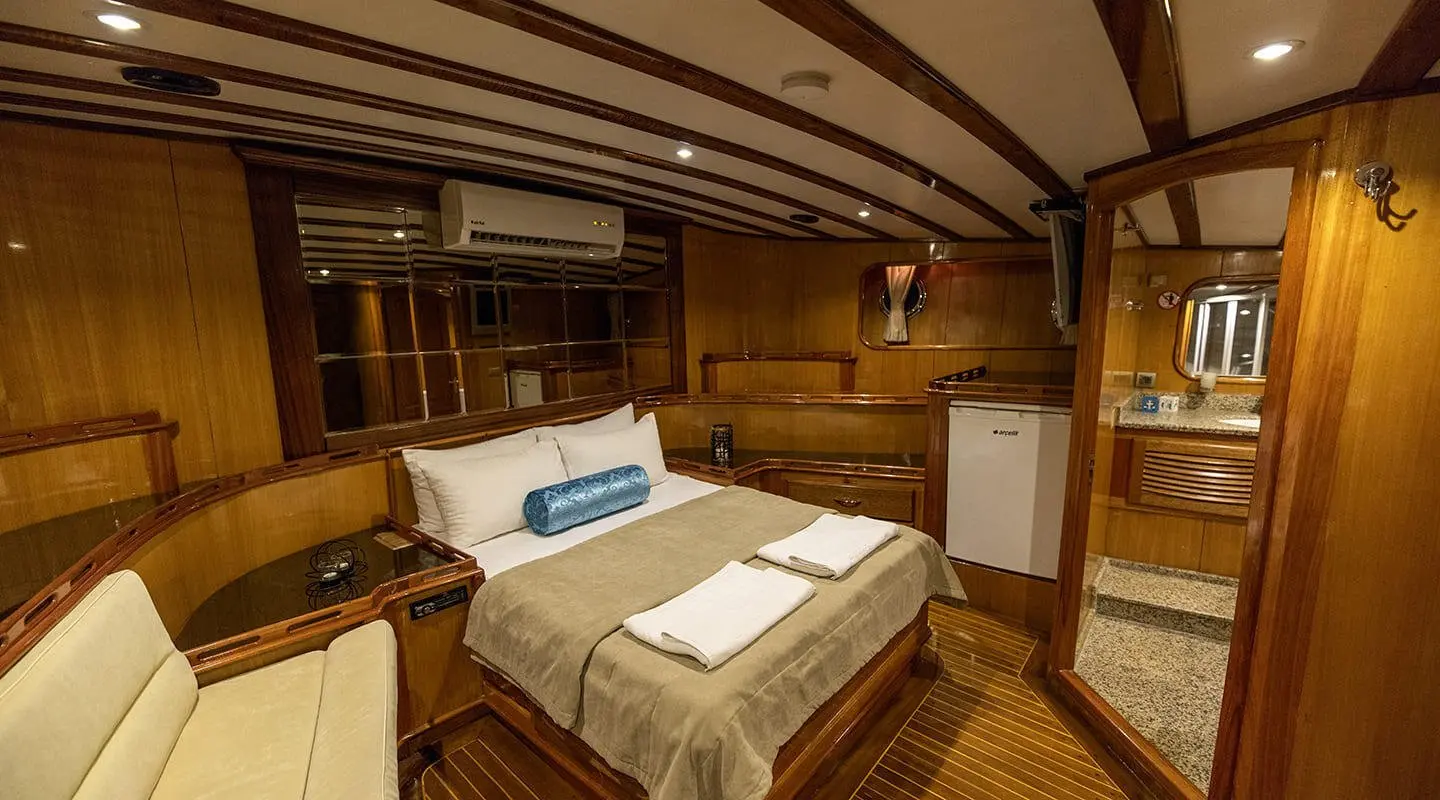 Kayhan 5 yacht interior with wood panels, beds, and warm lighting at sunset
