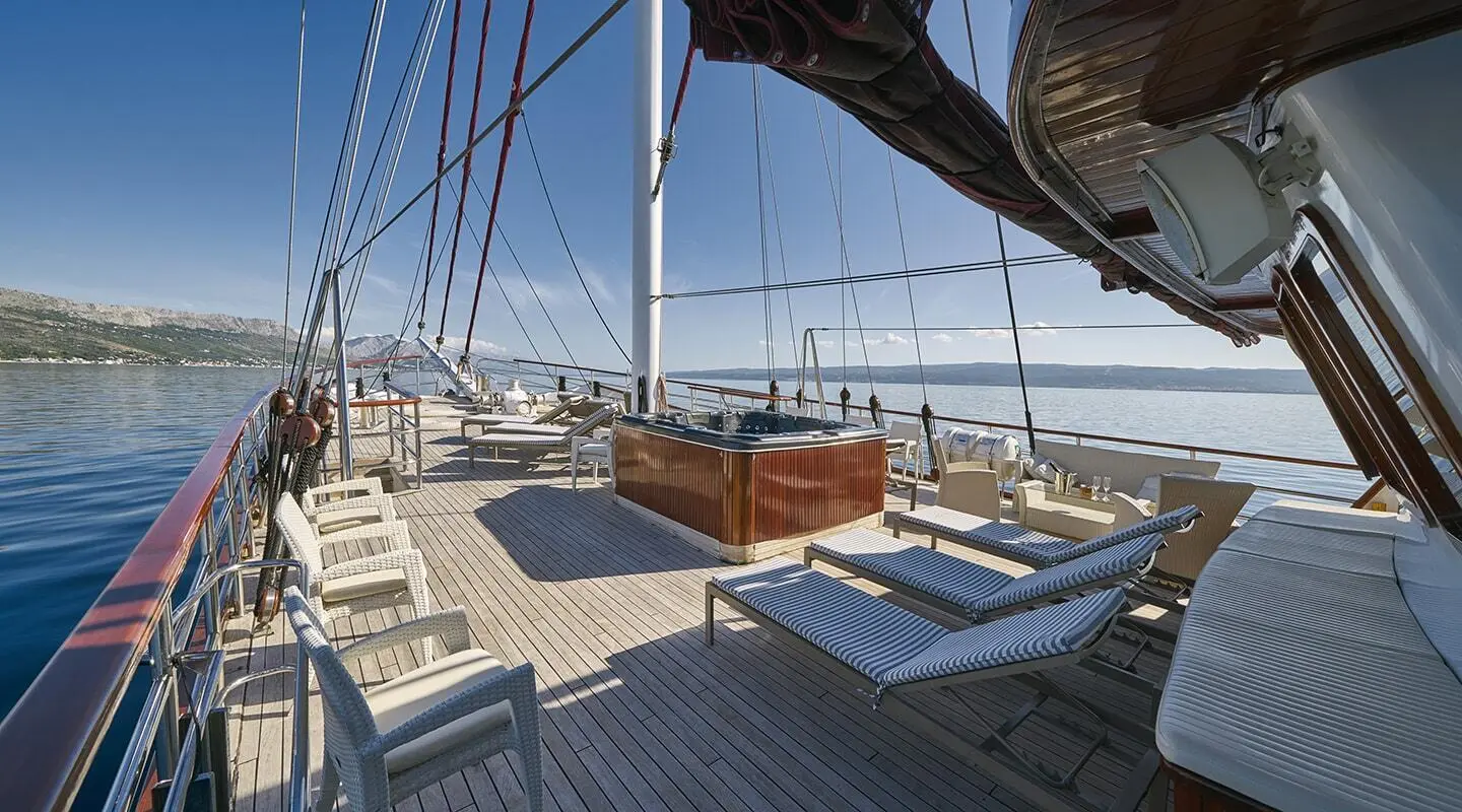 A teak deck with seating, ropes, and sail rigging on Amorena luxury yacht