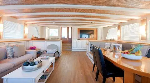 Cobra King yacht saloon interior with wooden floors, white seating, and a flat screen TV