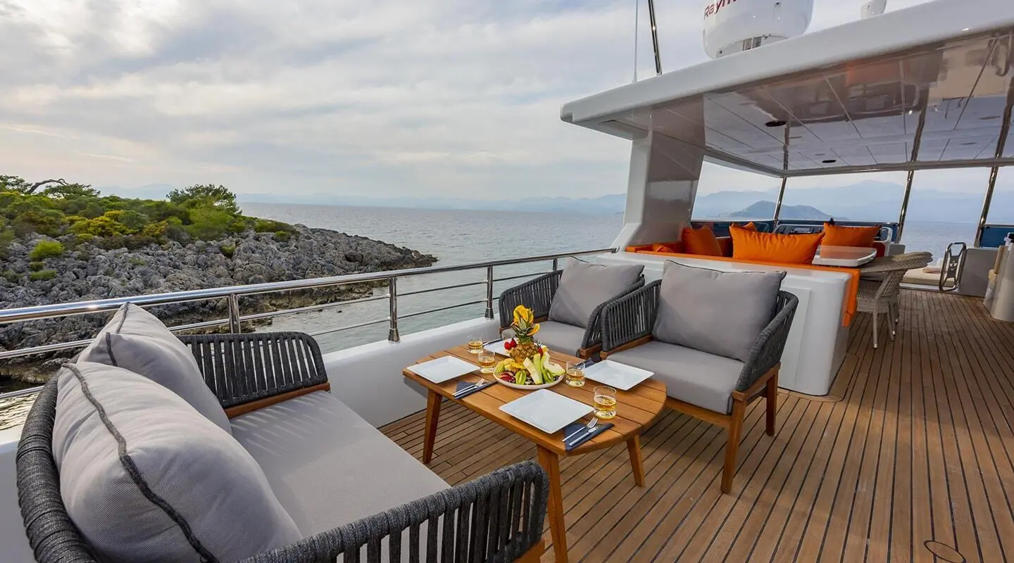 Yacht Simay M deck seating area with table and lounge chairs at sunset