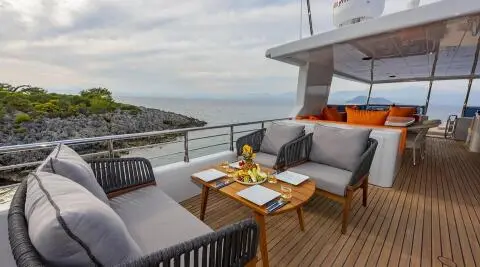 Yacht Simay M deck seating area with table and lounge chairs at sunset