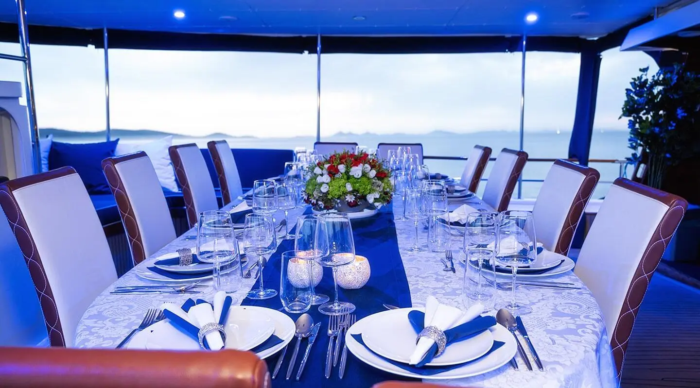 A blue-draped dining area on Aurum yacht with table set for guests