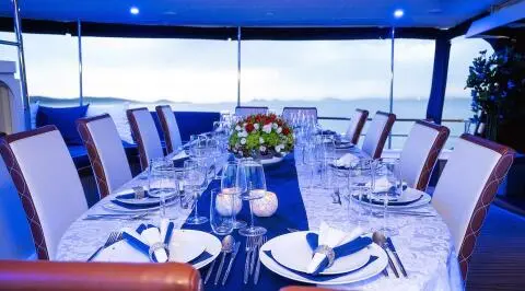 A blue-draped dining area on Aurum yacht with table set for guests
