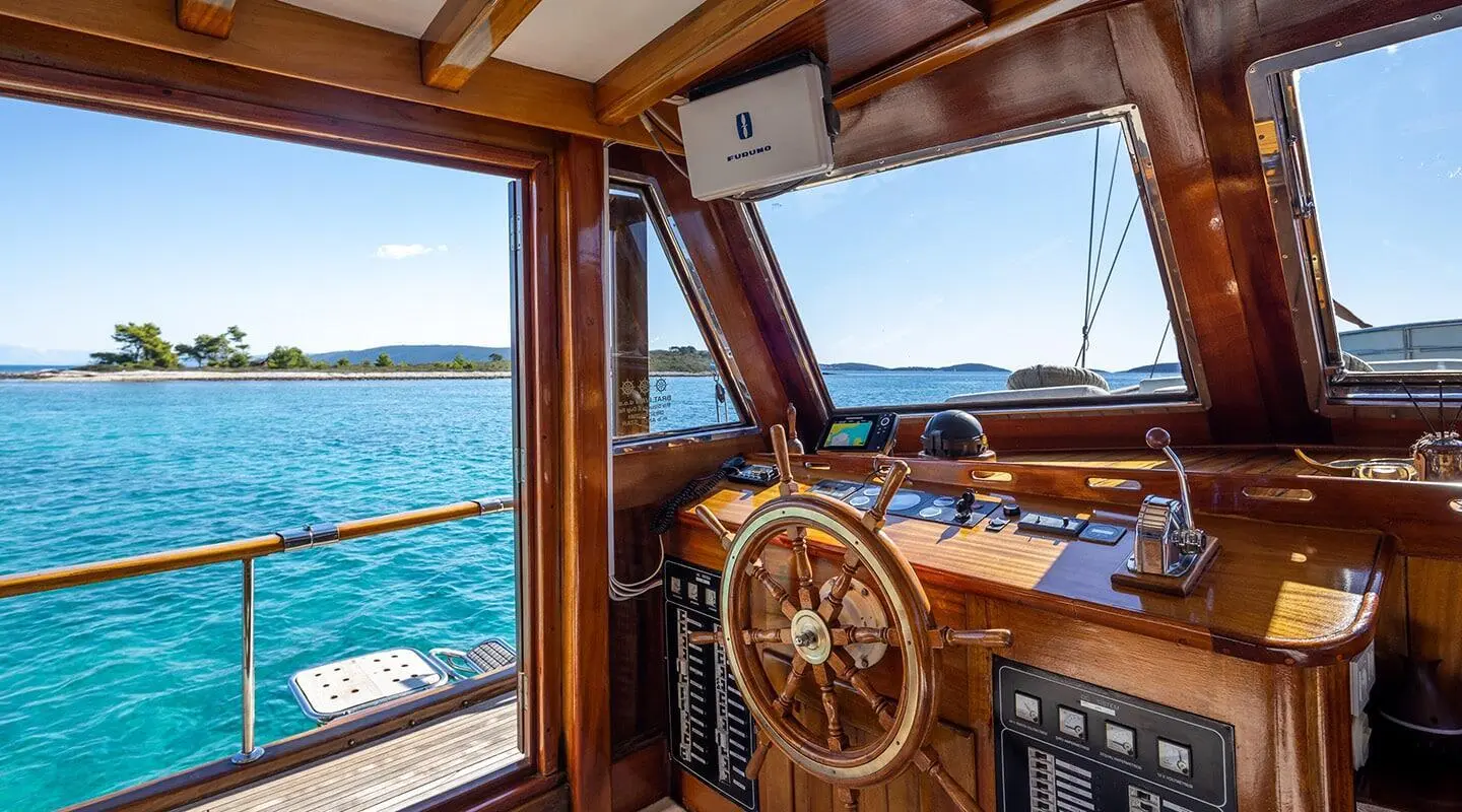 Front cockpit of a luxury yacht named Andi Star with wooden helm and sea horizon