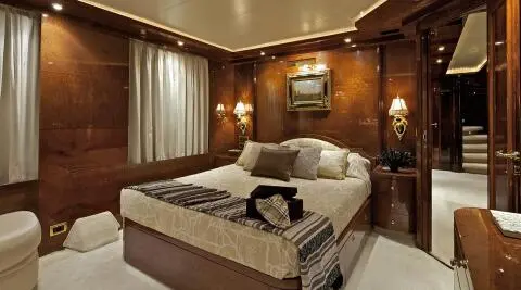 Luxurious master cabin aboard O'Rion yacht with polished wood panels and plush bedding