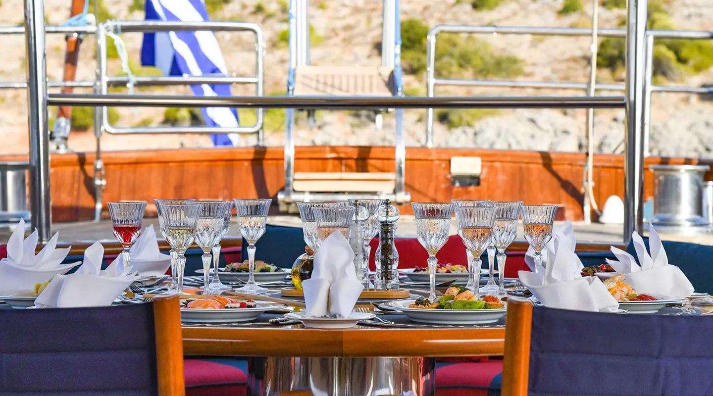 Tamarita yacht dining area at sunset with table settings and amber lighting