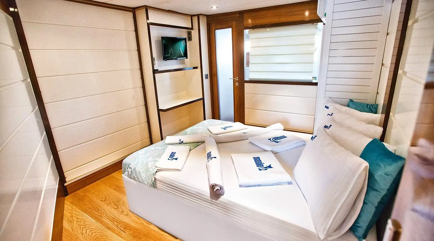 Maske 2 yacht bedroom with two single beds and wood panels at sunset