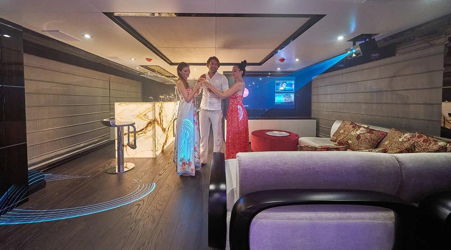 Interior of a yacht with people standing near seating and a ceiling skylight
