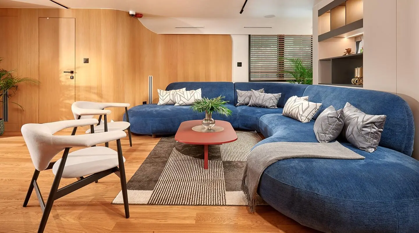 Interior of a living area with large blue sectional sofa and a red coffee table