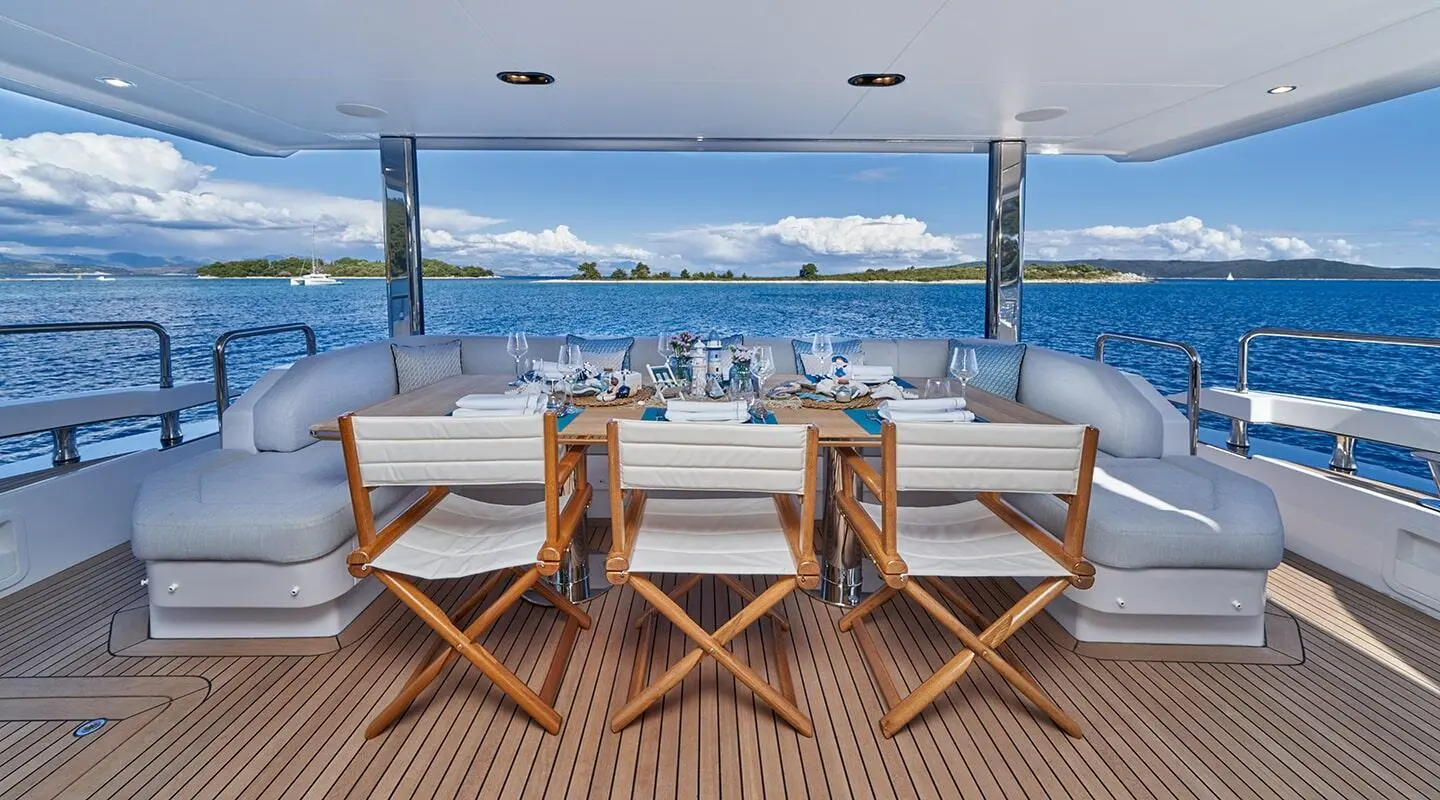 Aluminia Too yacht deck with dining area, sunset ocean view, wooden chairs