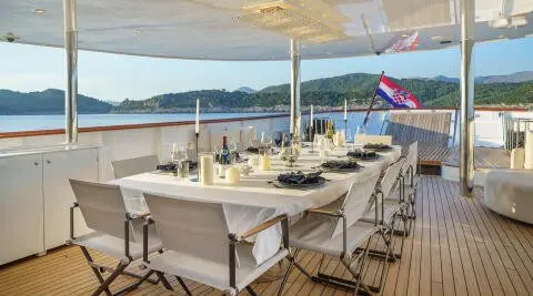 Maia yacht dining area on deck at sunset with table set and chairs