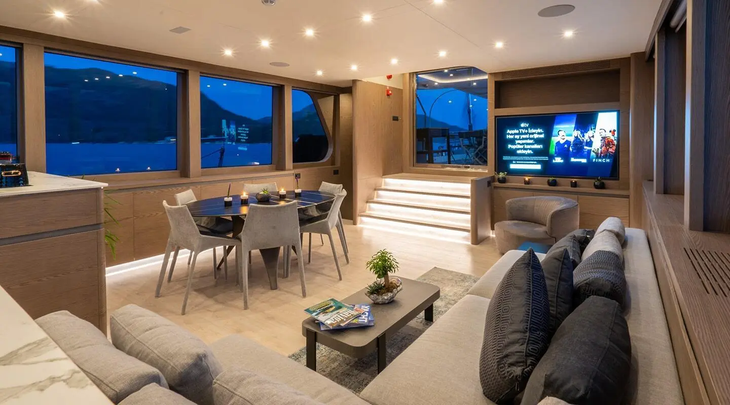 Interior of a yacht saloon with seating, dining table, and large windows