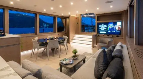 Interior of a yacht saloon with seating, dining table, and large windows