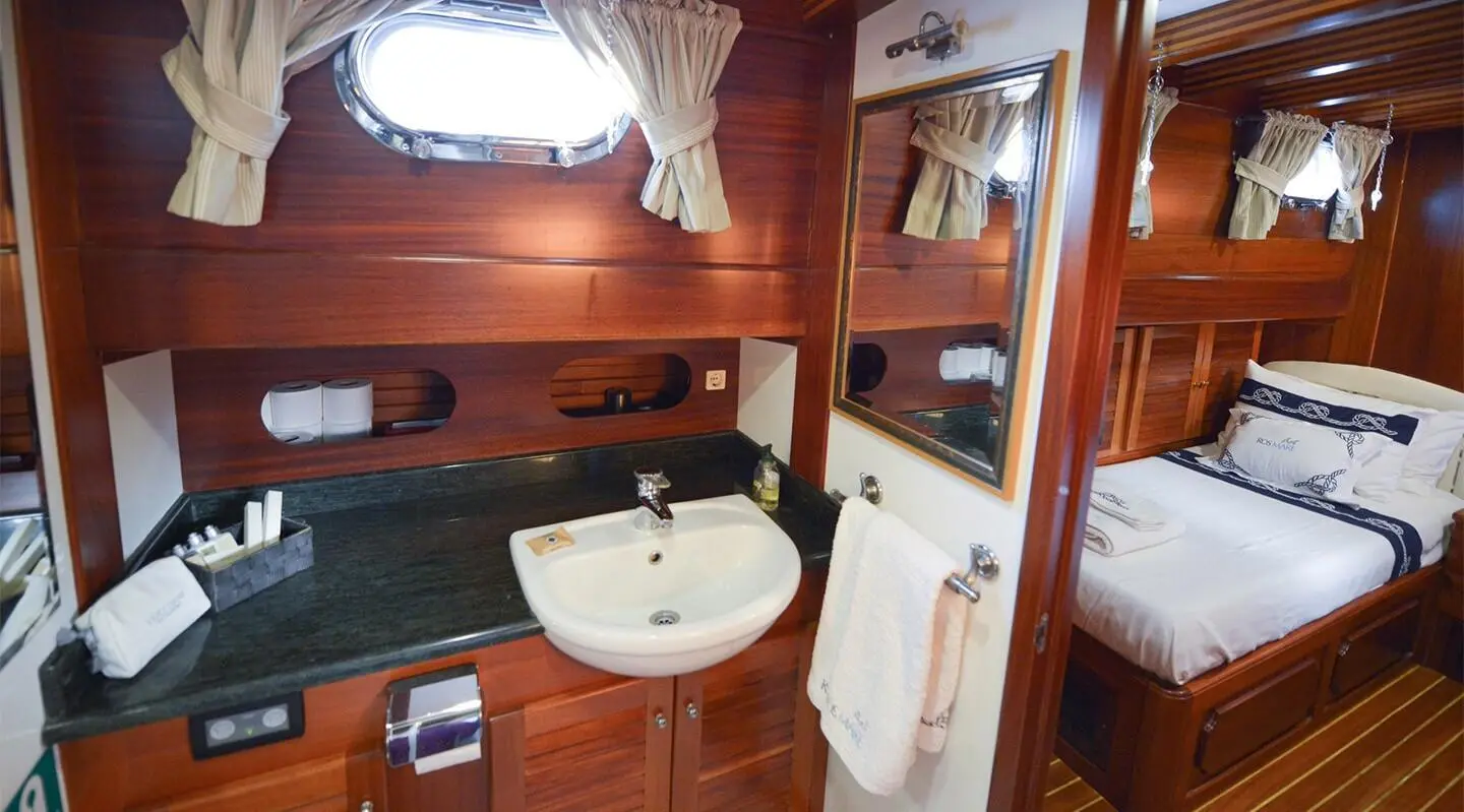 Ros Mare stylish onboard bathroom with wood paneling, sink, mirror, and towels